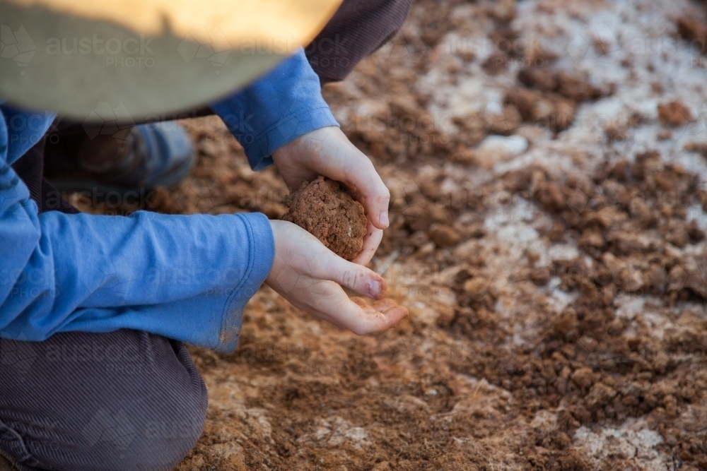 Young boy rolling clay in his hands - Australian Stock Image