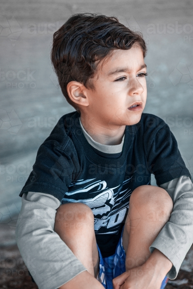 Young boy seated looking away - Australian Stock Image