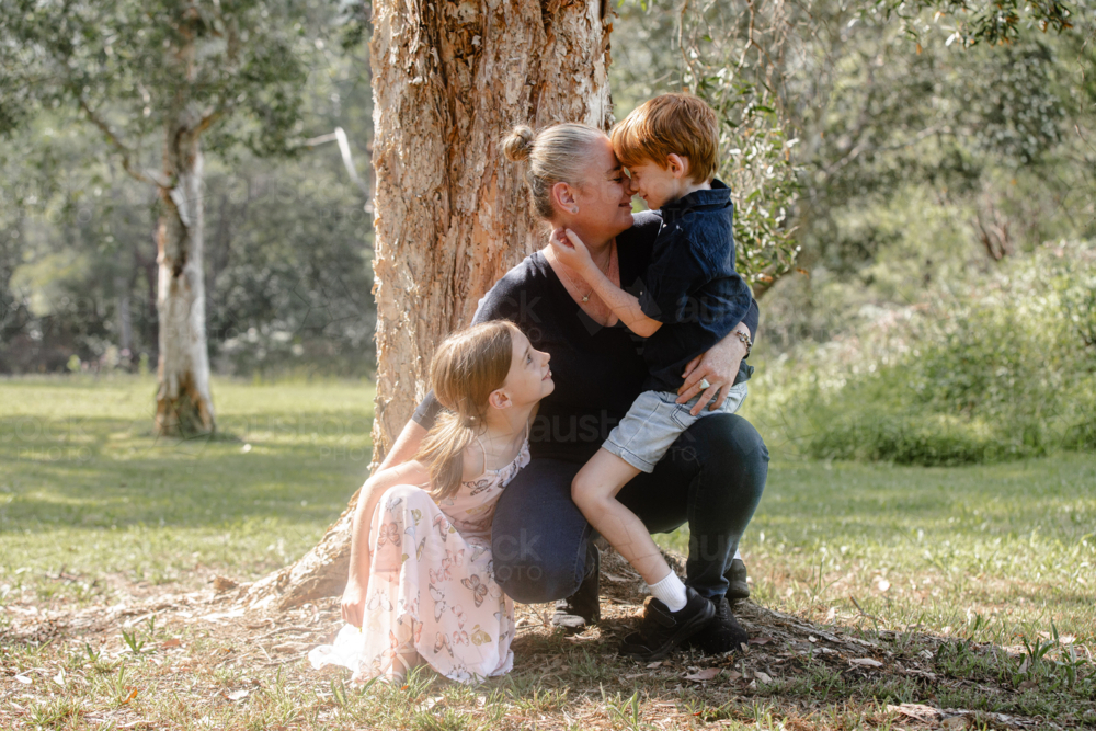 Young boy sitting mother's lap while crouching on the ground - Australian Stock Image