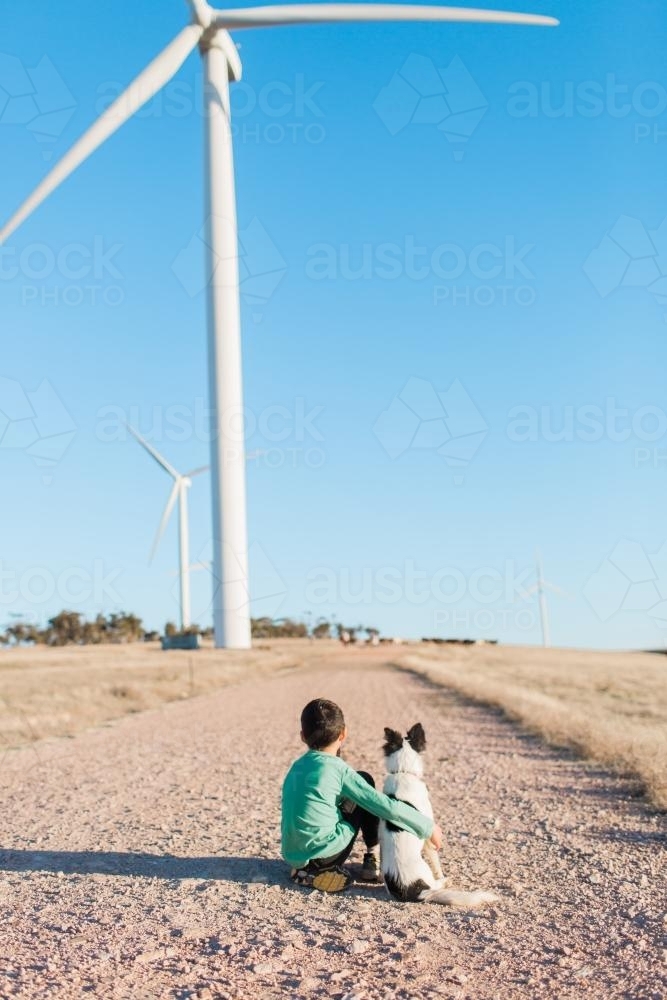 young boy sitting next to a dog on a farm - Australian Stock Image