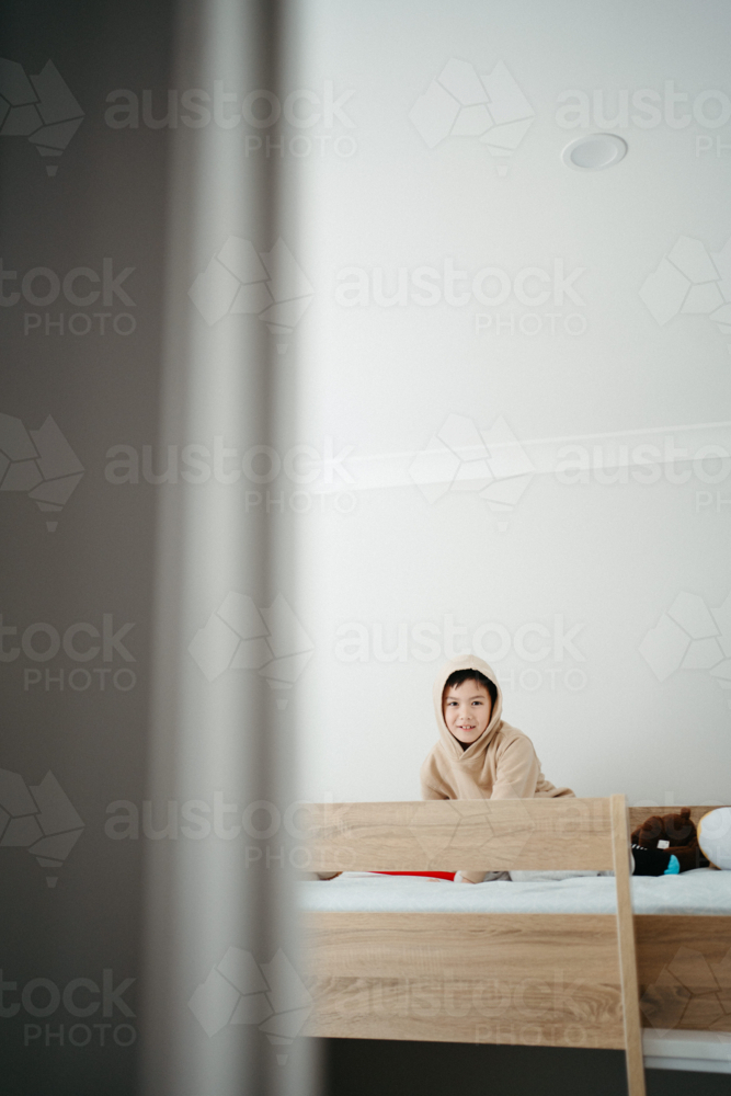 Young boy sitting on top of the bunk bed. - Australian Stock Image
