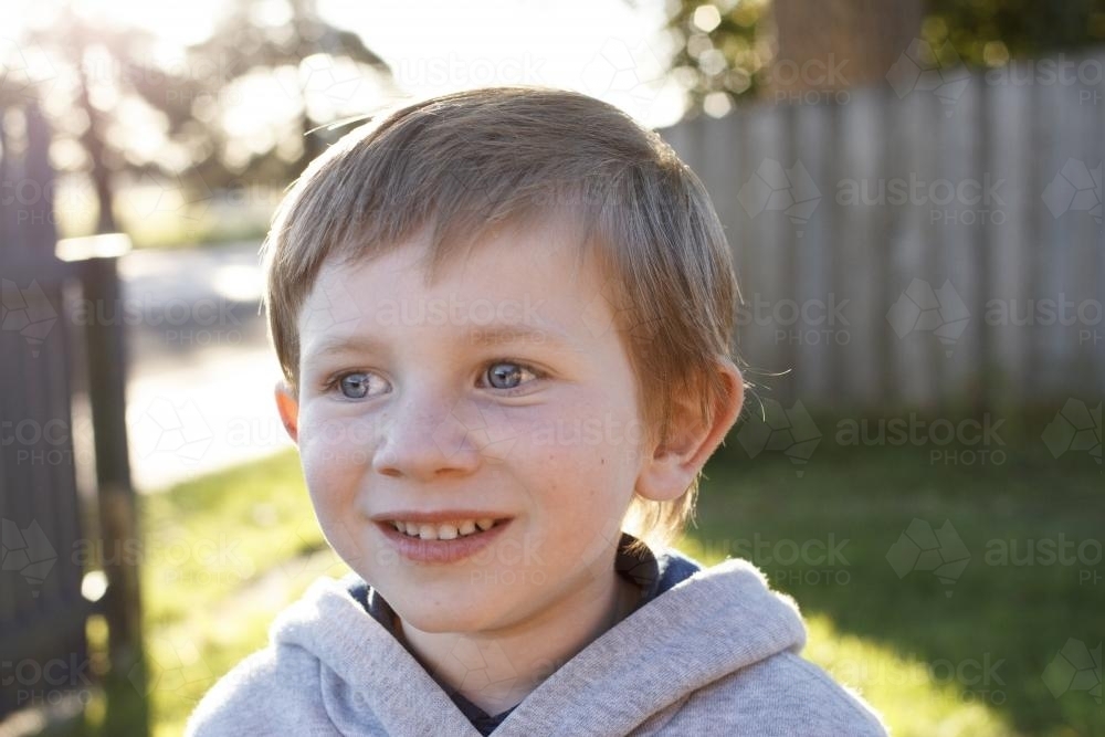 Young boy smiling in afternoon sun - Australian Stock Image