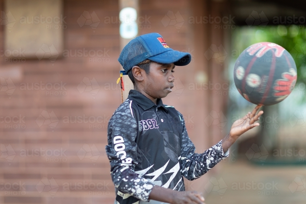 young boy spinning a basketball on his finger - Australian Stock Image