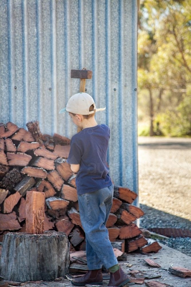 Young boy splitting wood for the fire - Australian Stock Image
