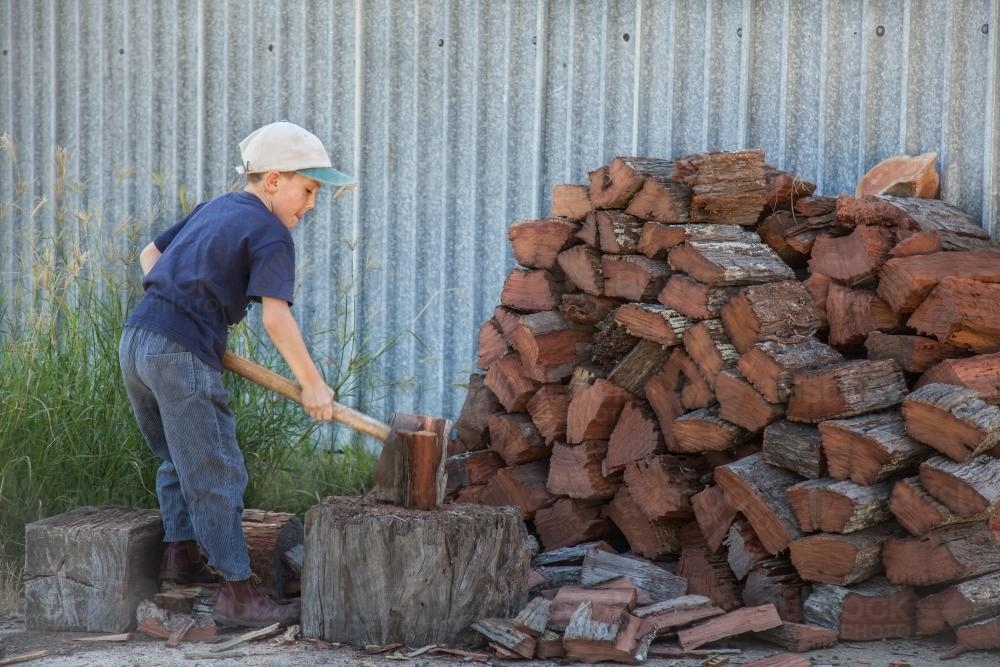 Young boy splitting wood for the fire - Australian Stock Image