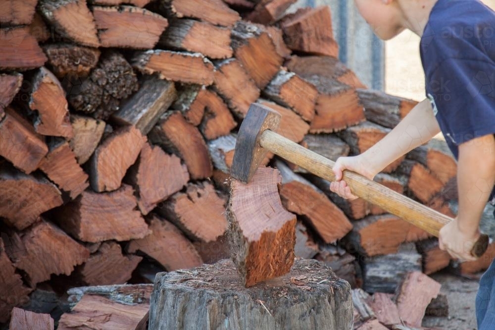 Young boy splitting wood for the fire - Australian Stock Image