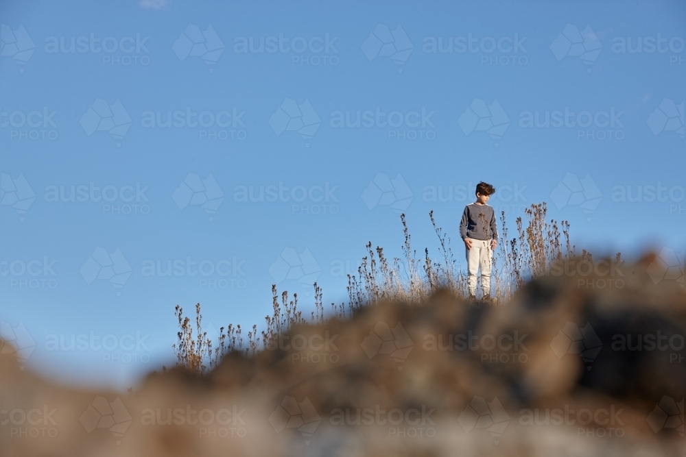 Young boy standing on hill top - Australian Stock Image