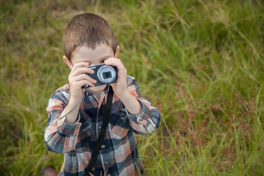 Young boy taking photos with a point and shoot camera - Australian Stock Image