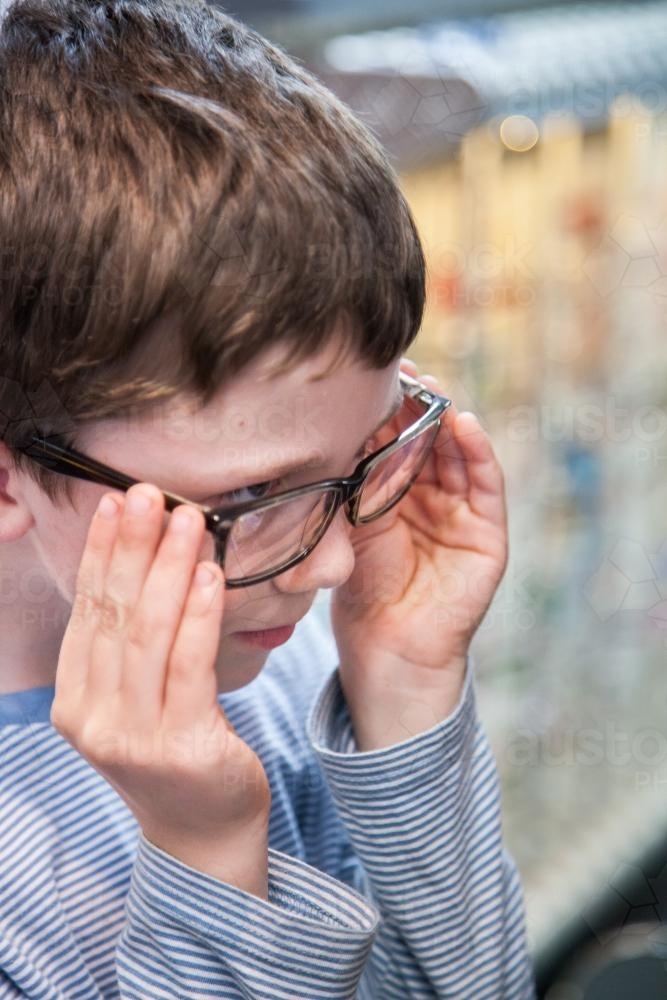 Young boy trying on different frames for new glasses - Australian Stock Image