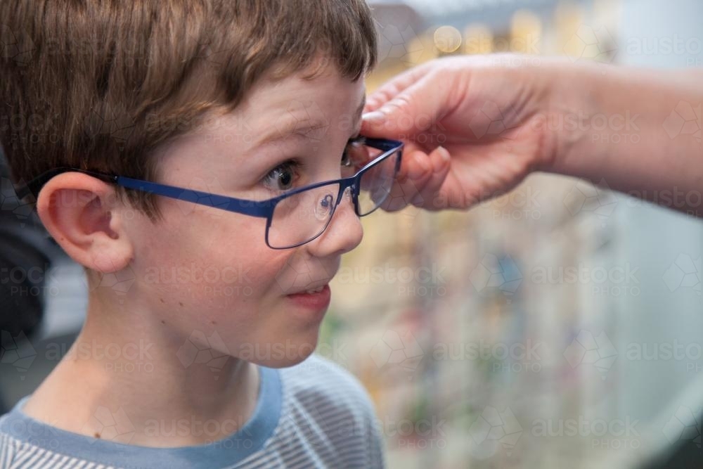 Young boy trying on different frames for new glasses - Australian Stock Image