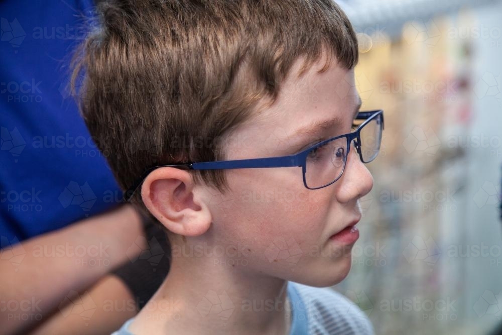 Young boy trying on different frames for new glasses - Australian Stock Image