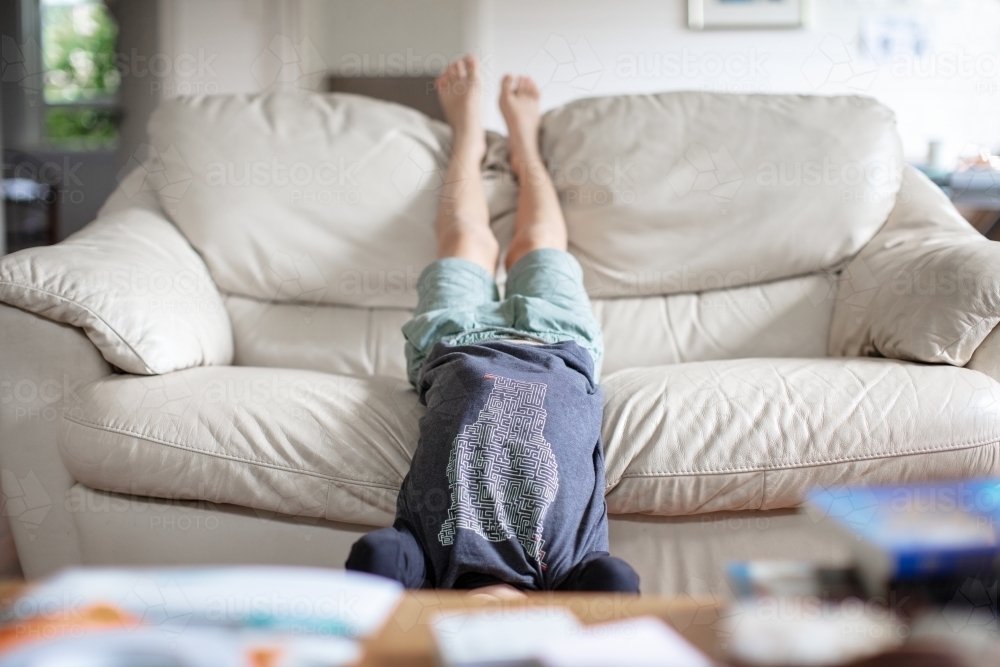 Young boy upside down on sofa - Australian Stock Image