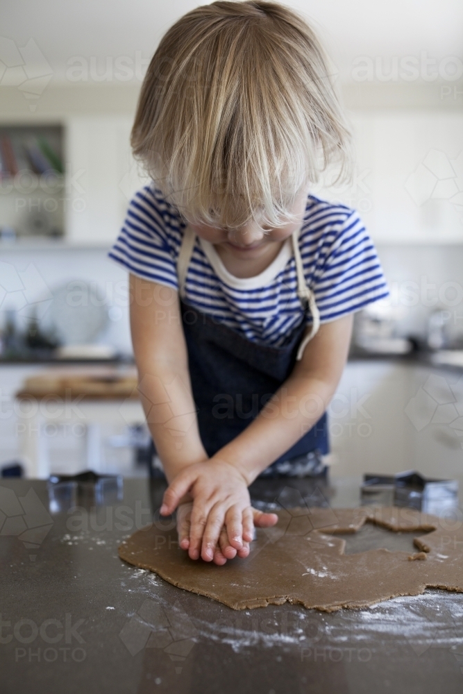 Young boy using cookie cutter to make gingerbread cookies - Australian Stock Image