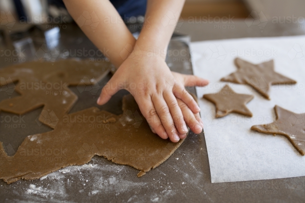 Young boy using cookie cutter to make gingerbread cookies - Australian Stock Image