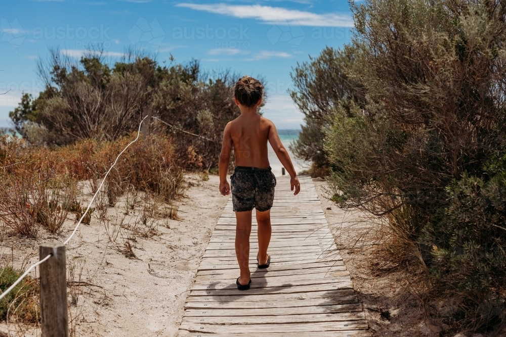 Young boy walking down a path to the beach - Australian Stock Image