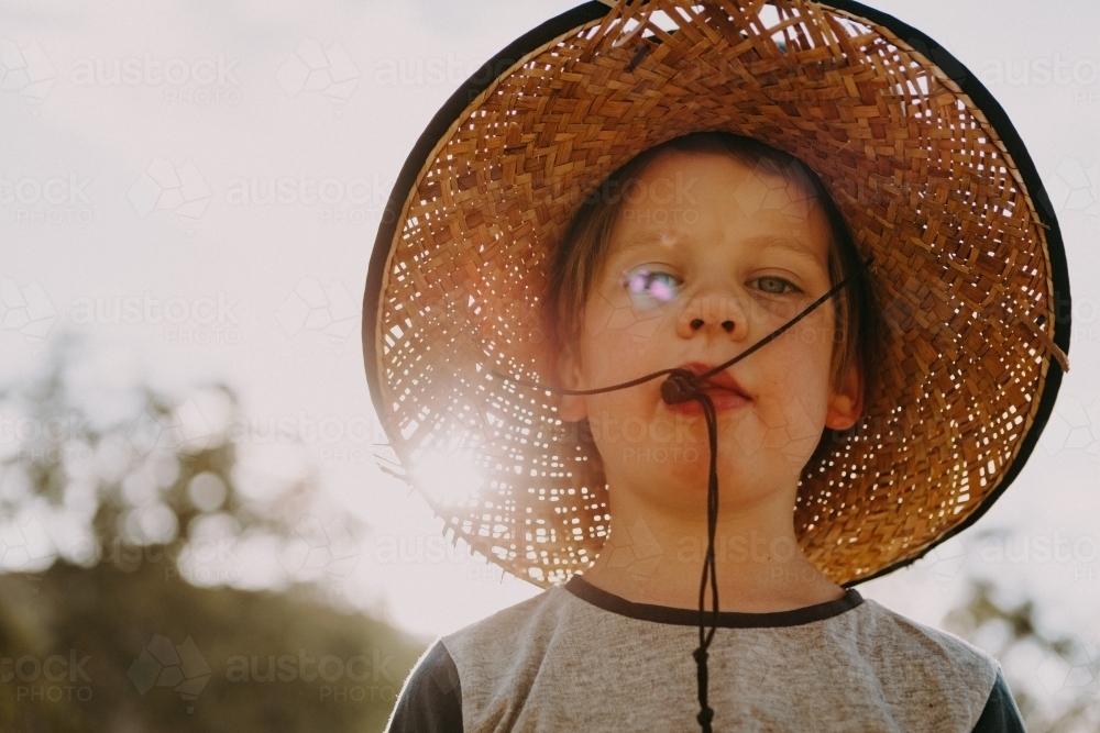 Young boy wearing a straw hat - Australian Stock Image
