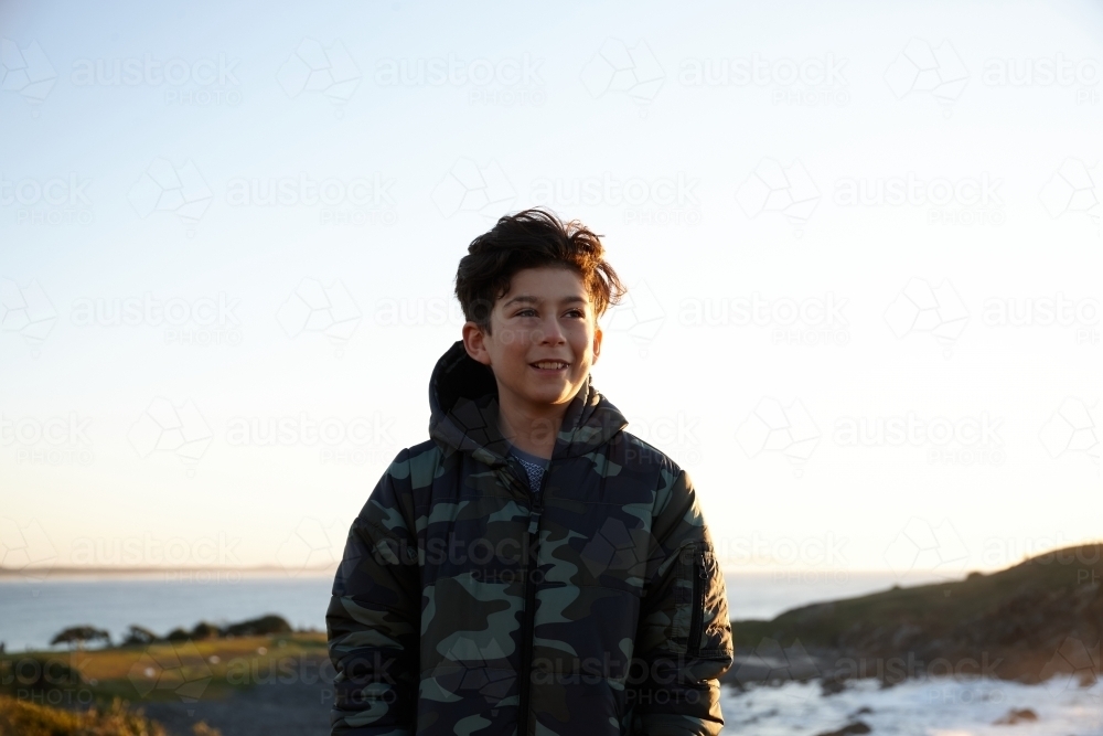 Young boy wearing camo jacket on sunrise - Australian Stock Image