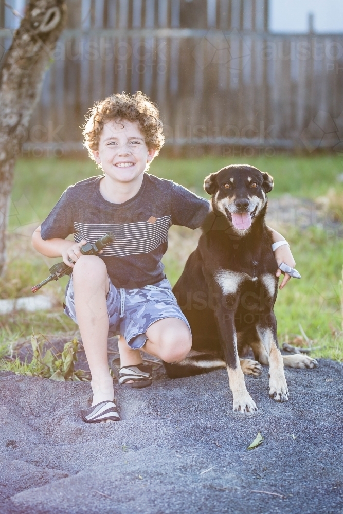 Young boy with arm around black and tan kelpie dog - Australian Stock Image
