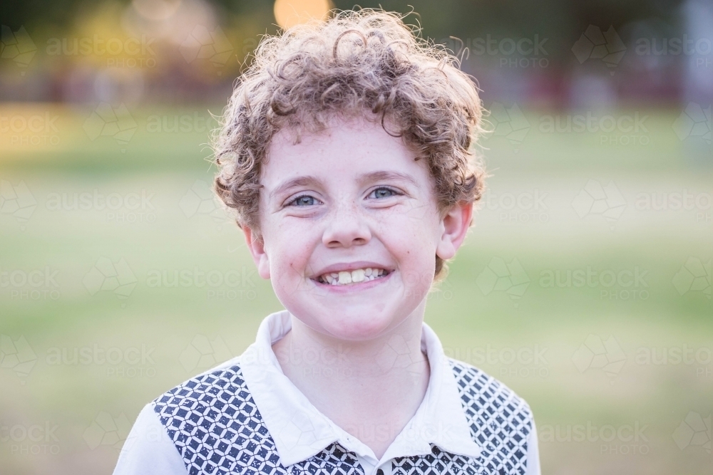 Young boy with curly hair happy smiling - Australian Stock Image