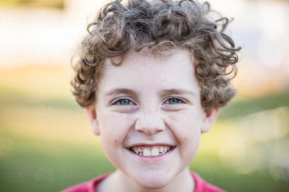 Young boy with curly hair with big smile - Australian Stock Image