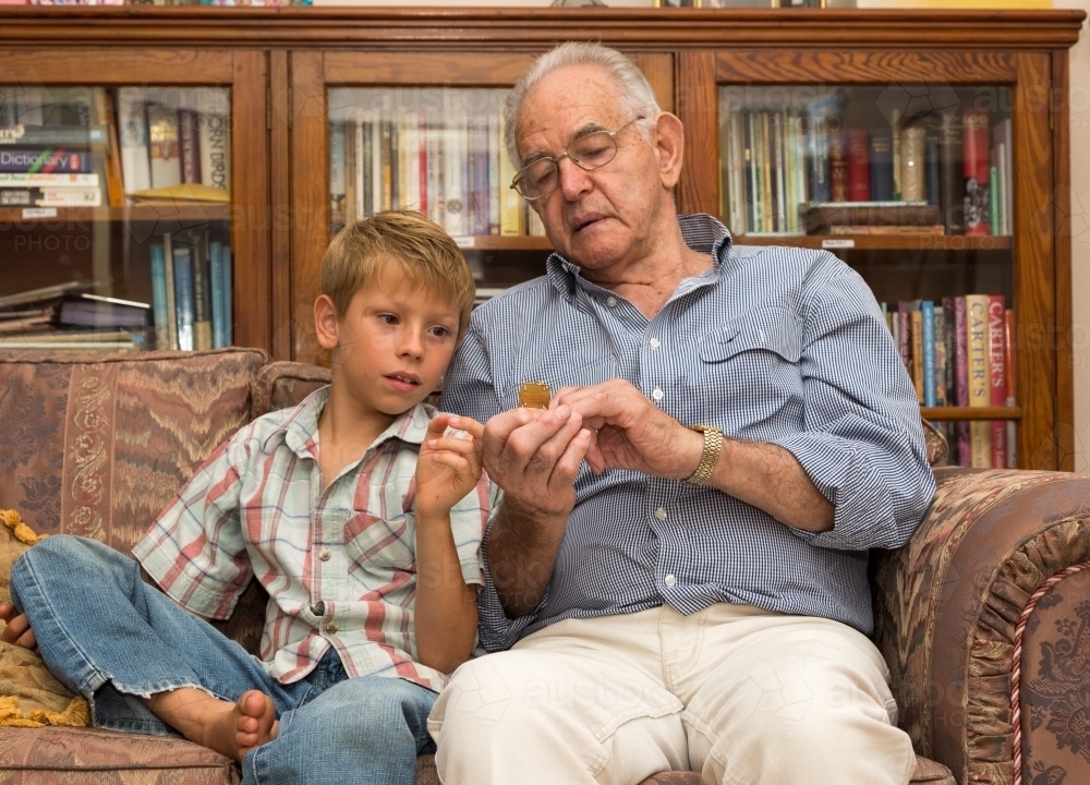 Young boy with grandfather on couch - Australian Stock Image
