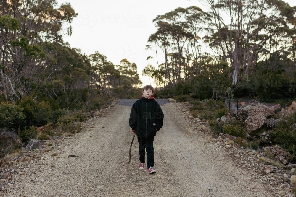 Young boy with stick on walking path - Australian Stock Image