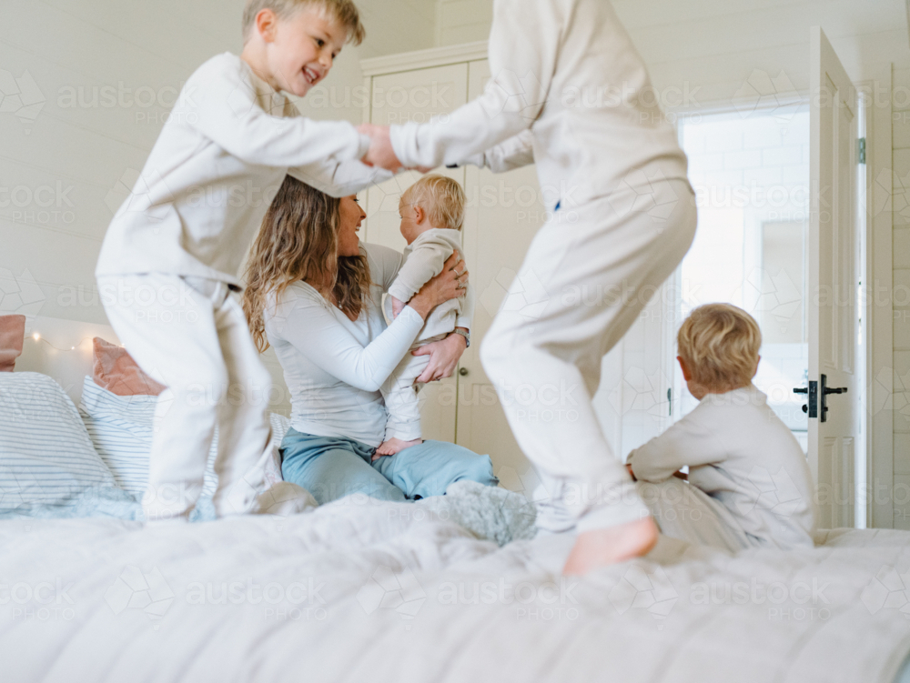 Young boys playing on the bed jumping - Australian Stock Image