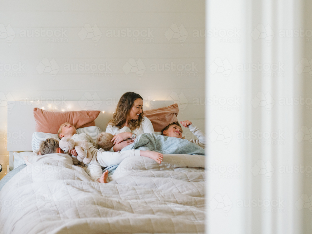 Young boys snuggling with mum on the bed - Australian Stock Image