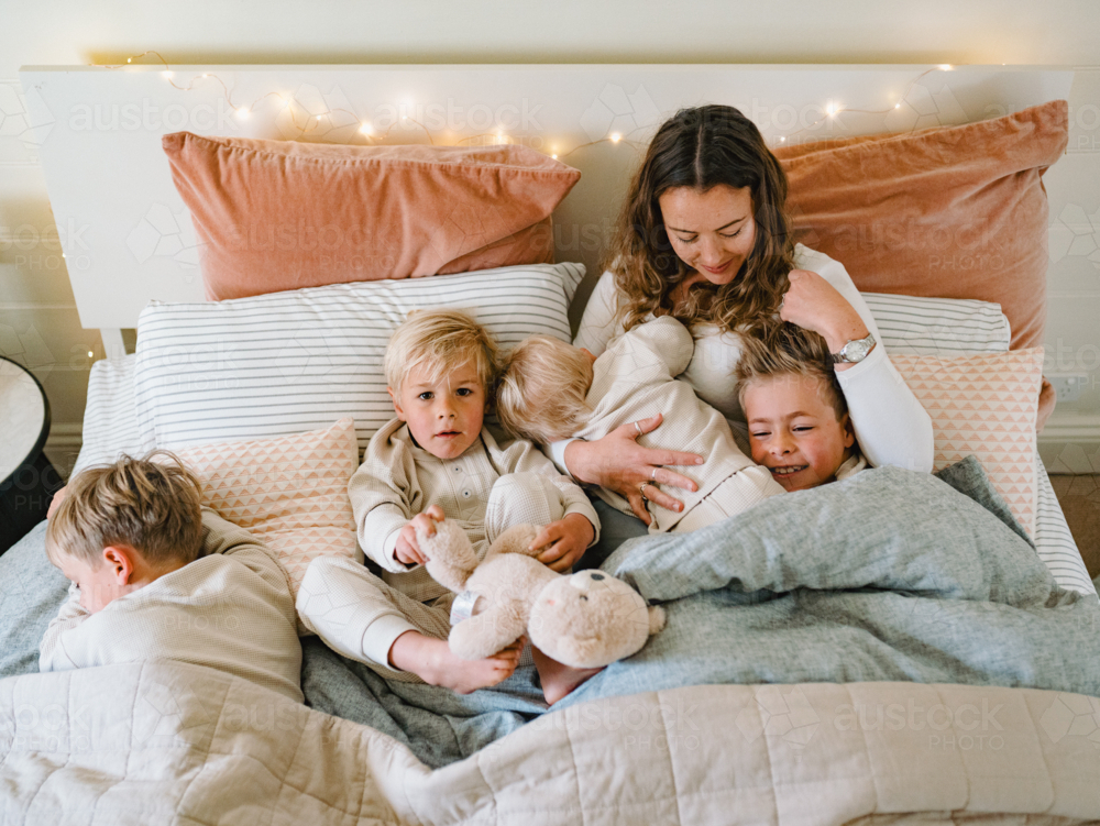 Young boys snuggling with mum on the bed - Australian Stock Image