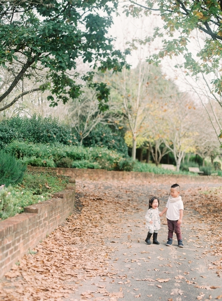 Young brother and sister holding hands in gorgeous park - Australian Stock Image