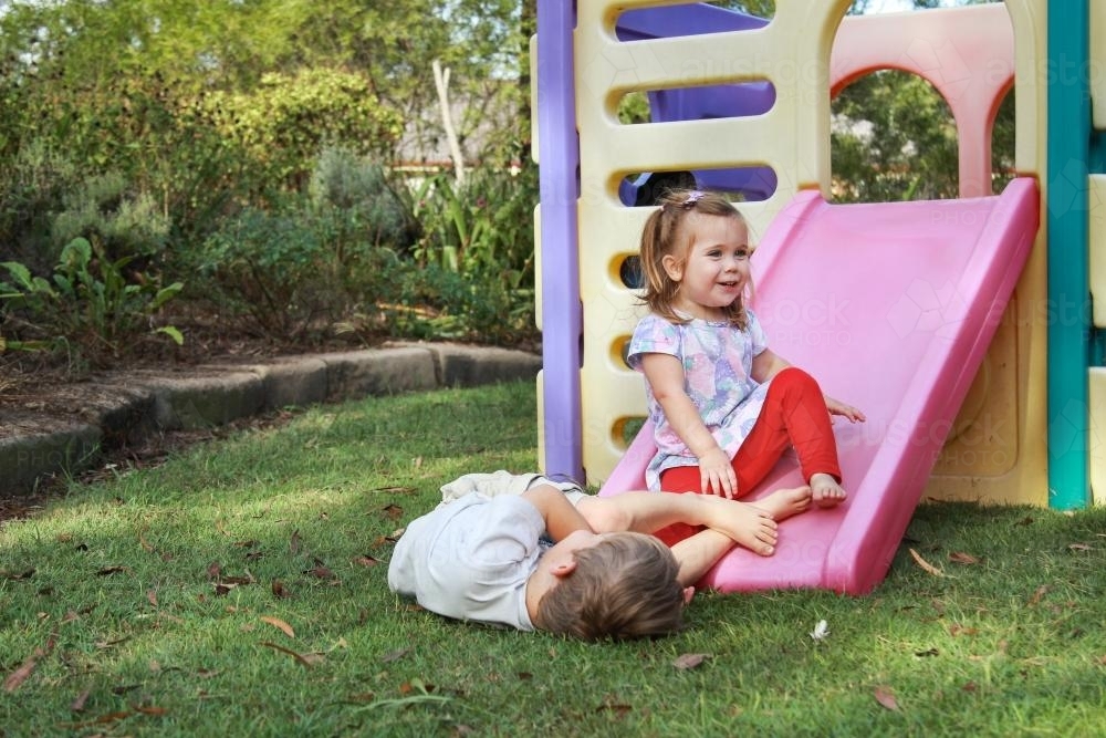 Young brother and sister playing together on a slide and play castle - Australian Stock Image