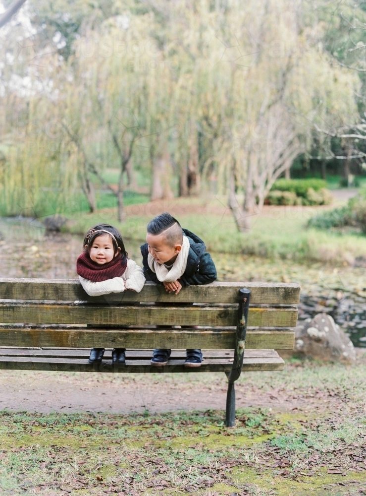 Young brother and sister standing on wooden bench in gorgeous outdoor surrounds - Australian Stock Image