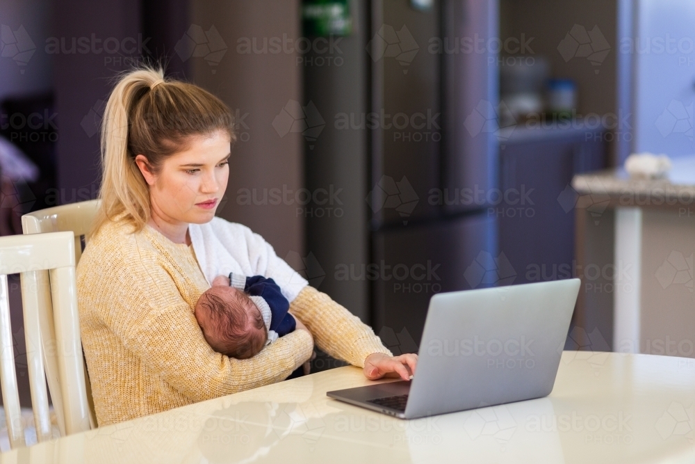 Young businesswoman mum working from home on laptop with newborn baby - Australian Stock Image