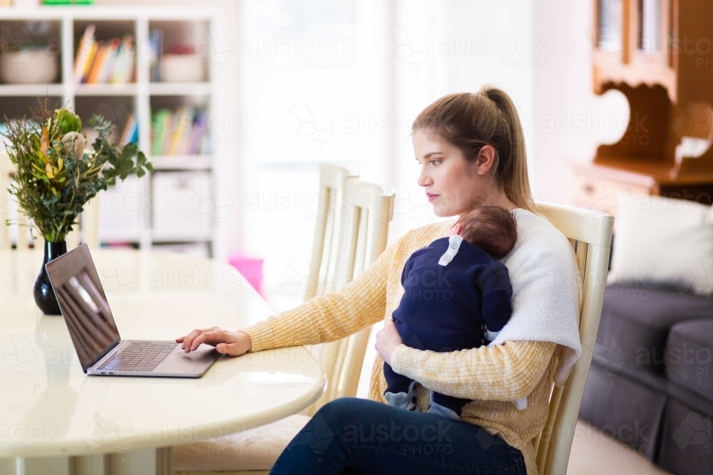 Young businesswoman mum working from home on laptop with newborn baby - Australian Stock Image