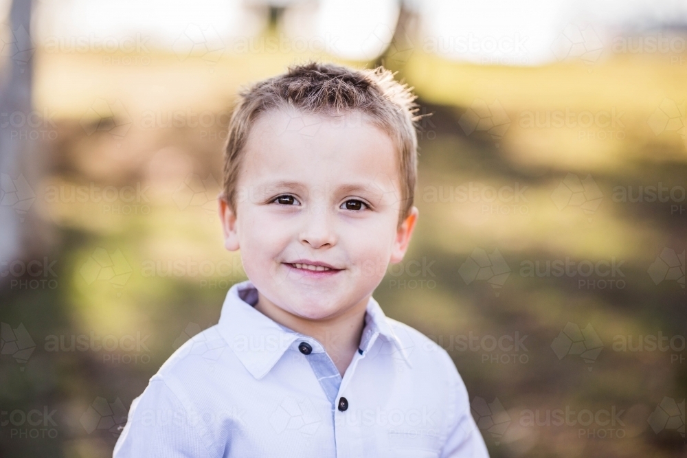 Young caucasian boy with brown eyes smiling shyly - Australian Stock Image