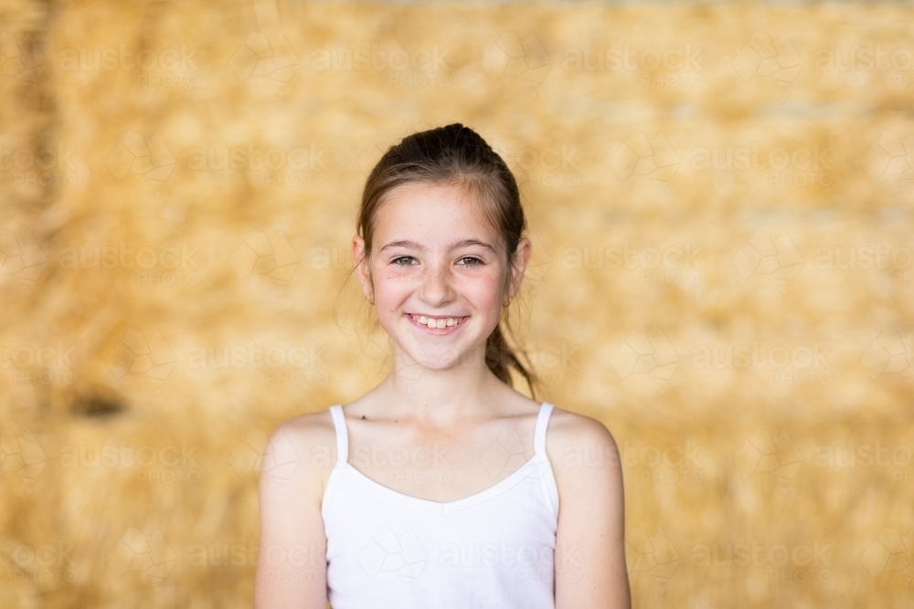 young caucasian girl with hair tied back wearing white singlet - Australian Stock Image