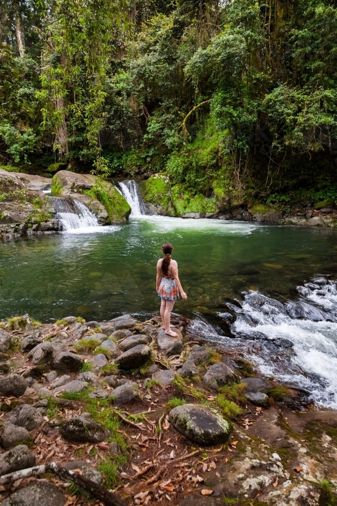 Young caucasian woman at the edge of a peaceful river pool in forest - Australian Stock Image
