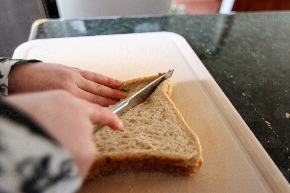 Young child cutting sandwich - Australian Stock Image