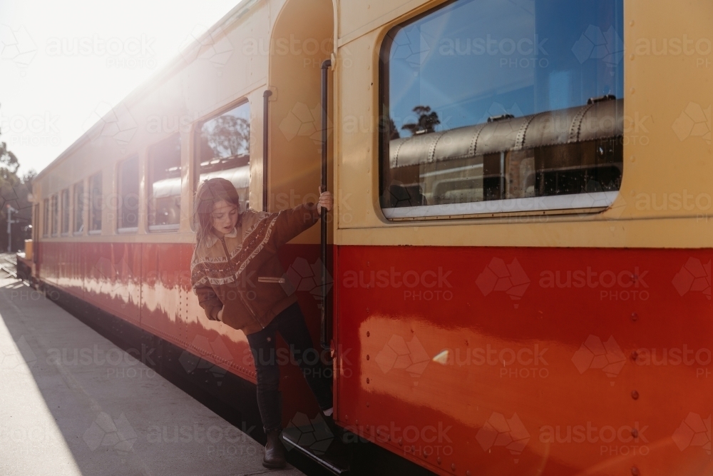 Young child hanging from doorway on rustic train - Australian Stock Image