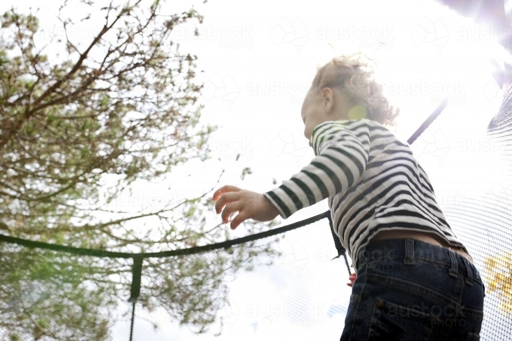 Young child jumping on trampoline - Australian Stock Image