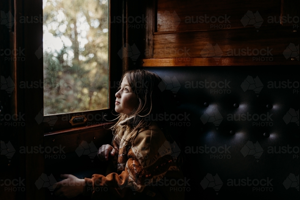 Young child looking out of window on dark train - Australian Stock Image