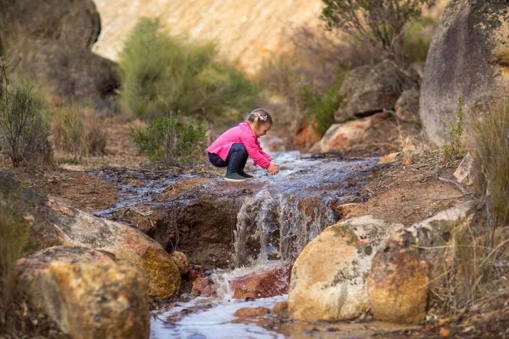 Young child playing in a creek - Australian Stock Image