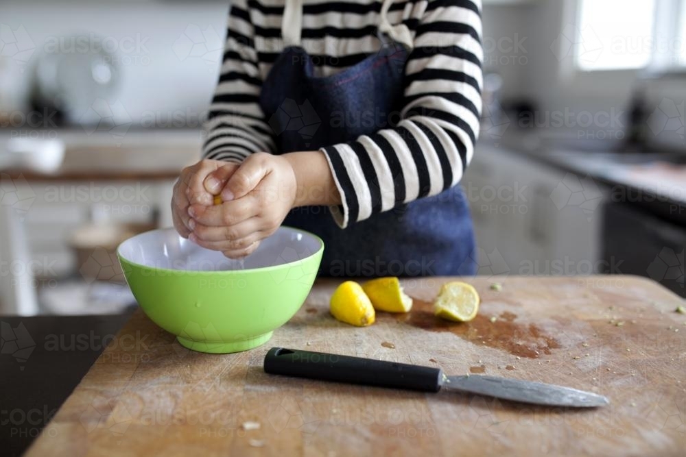 Young child squeezing lemons into a bowl - Australian Stock Image