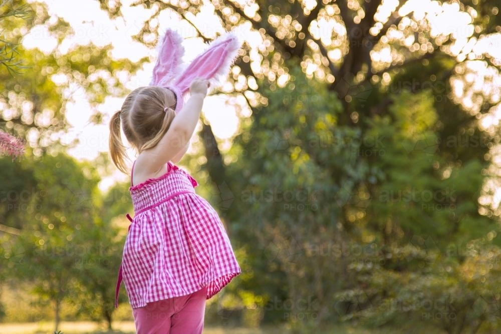 Young child wearing Easter bunny ears outdoors - Australian Stock Image