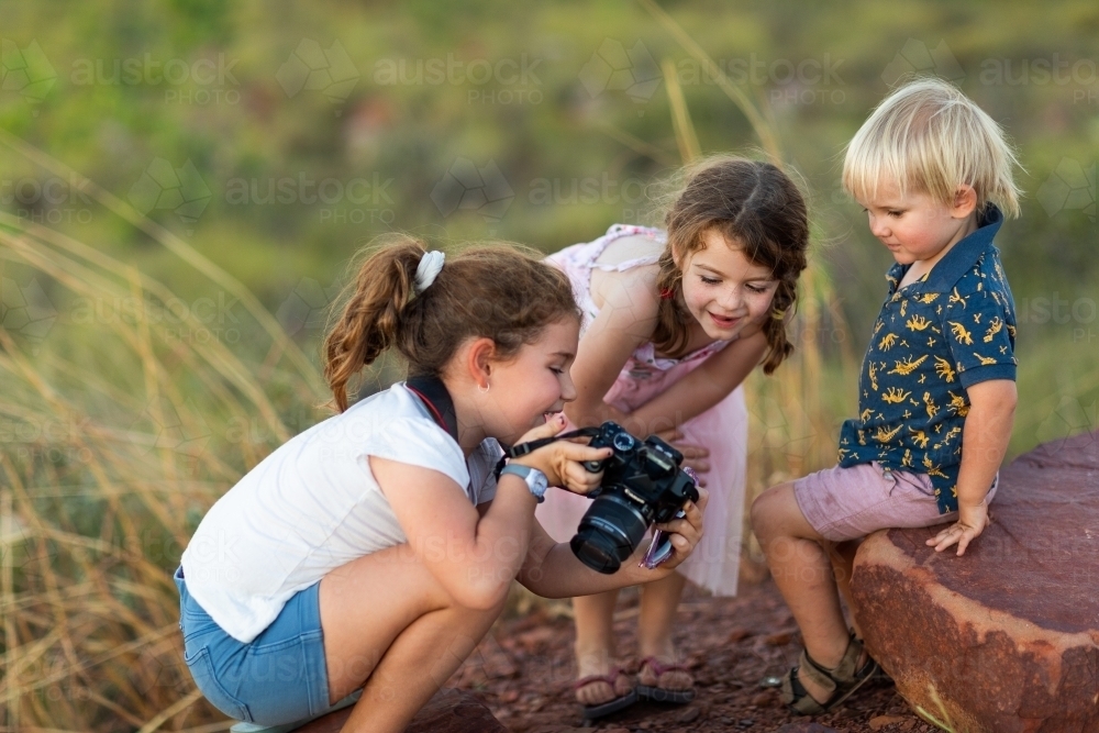 young children looking at photo on back of camera - Australian Stock Image