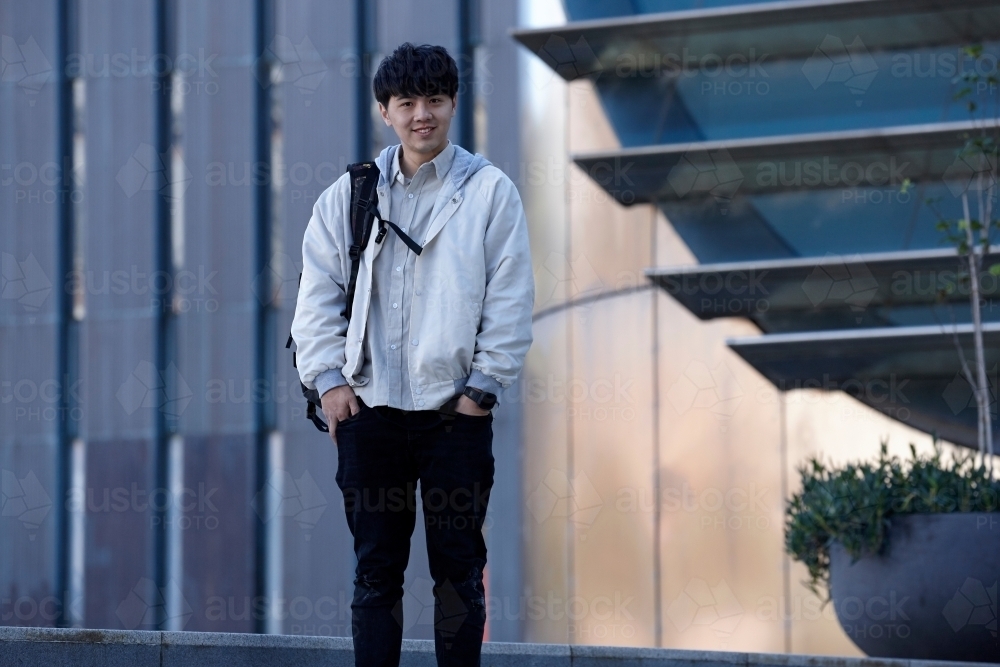 Young Chinese student standing on stairs at university campus - Australian Stock Image