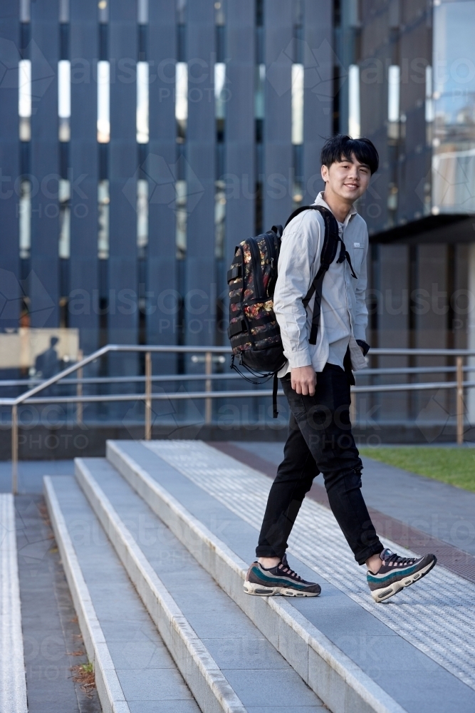 Young Chinese student walking on stairs at university campus - Australian Stock Image