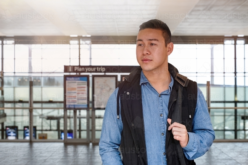 Young commuter waiting above platform at train station - Australian Stock Image
