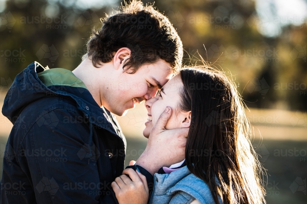 Young couple close together foreheads touching looking into each others eyes smiling - Australian Stock Image
