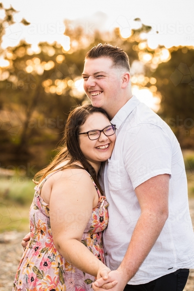 Young couple holding hands cuddling and laughing - Australian Stock Image